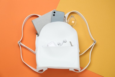 Photo of White backpack with different items on color background, flat lay