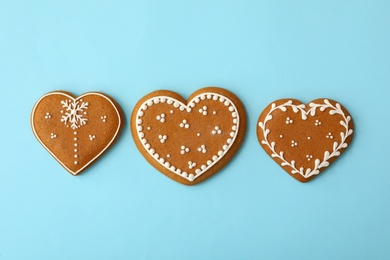 Photo of Christmas heart shaped gingerbread cookies on light blue background, flat lay