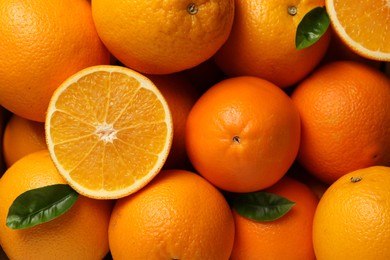 Many ripe oranges and green leaves as background, top view