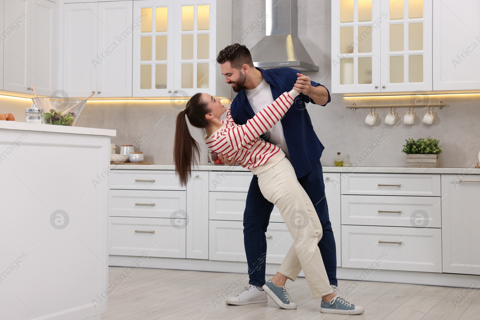 Photo of Happy lovely couple dancing together in kitchen