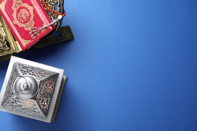 Photo of Arabic lantern and quran on blue background, flat lay. Space for text