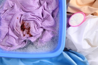 Garment and powdered detergent near basin with dirty clothes, top view. Hand washing laundry