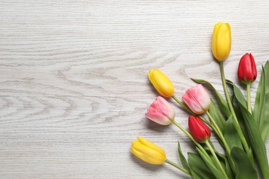 Photo of Beautiful colorful tulip flowers on white wooden table, flat lay. Space for text