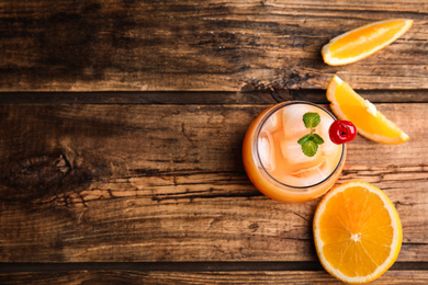 Photo of Fresh alcoholic Tequila Sunrise cocktail on wooden table, flat lay. Space for text