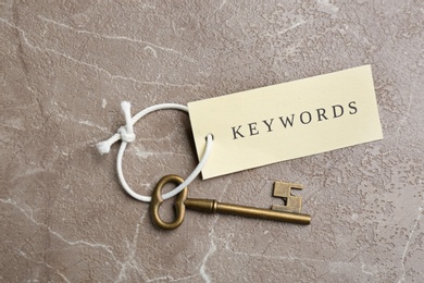 Vintage key and tag wIth word KEYWORDS on grey table, top view