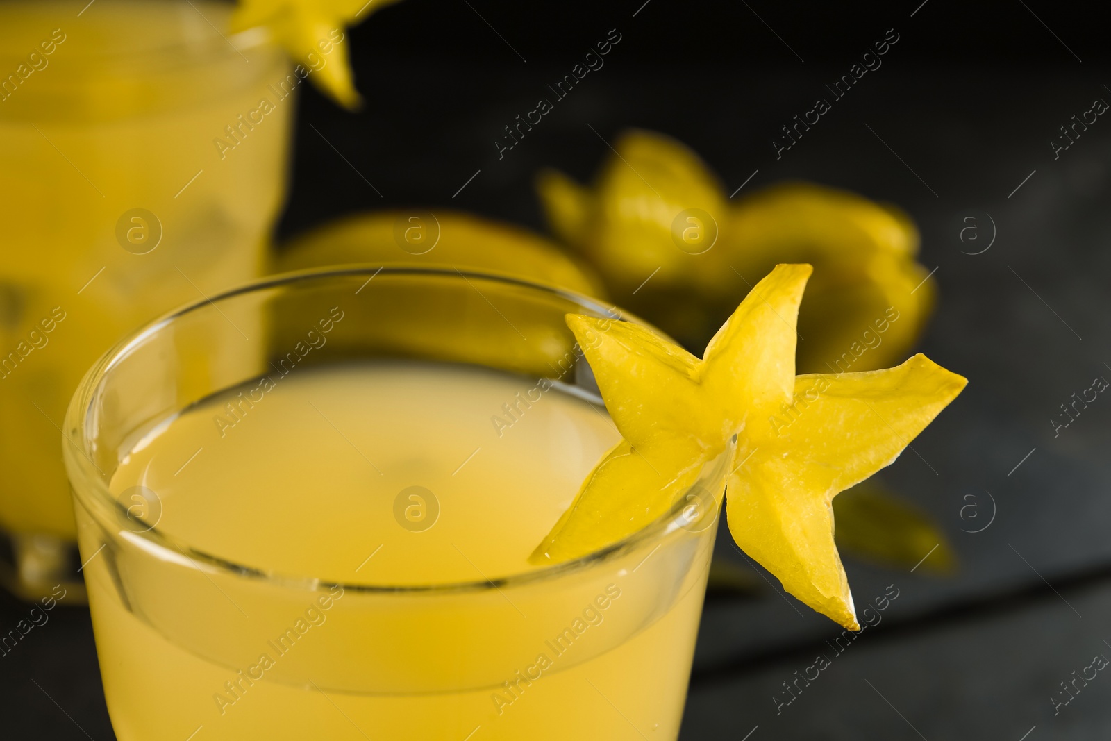 Photo of Delicious carambola juice in glass on table, closeup