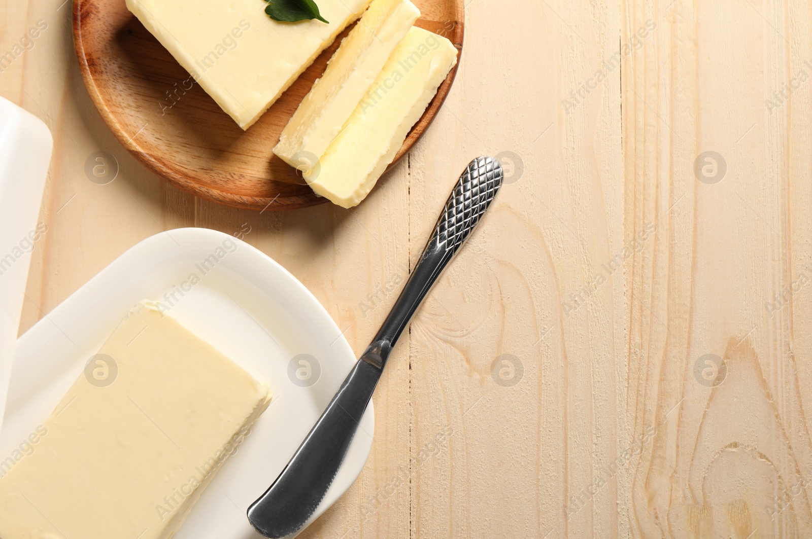 Photo of Tasty butter and knife on wooden table, flat lay. Space for text