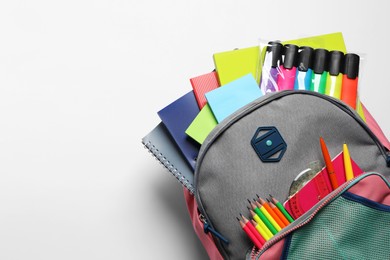 Photo of Backpack with different school stationery on white background, top view. Space for text