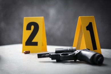 Handgun and crime scene markers on light grey marble table, closeup
