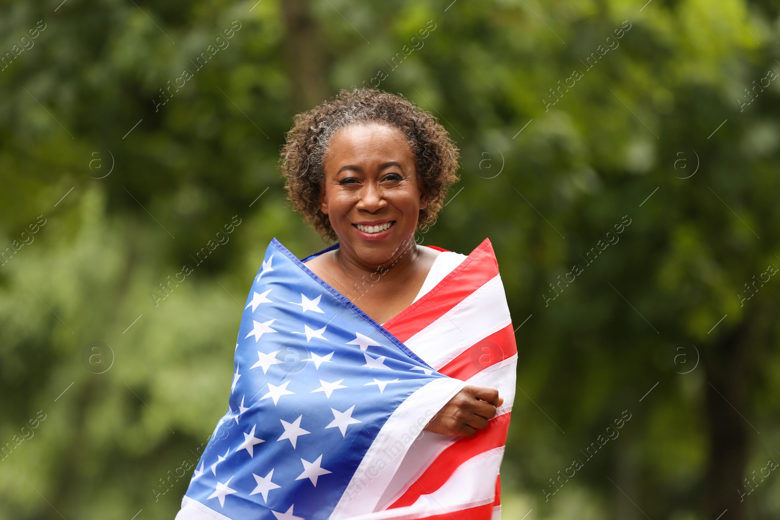 Photo of Portrait of happy African-American woman with USA flag in park