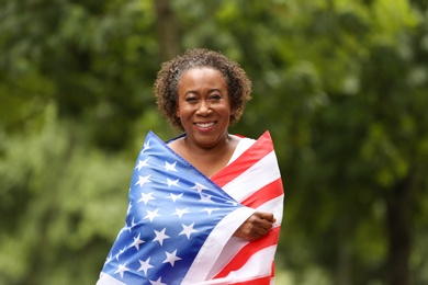 Photo of Portrait of happy African-American woman with USA flag in park