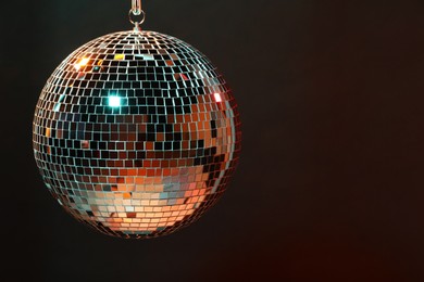 Photo of Shiny bright disco ball on dark background, space for text