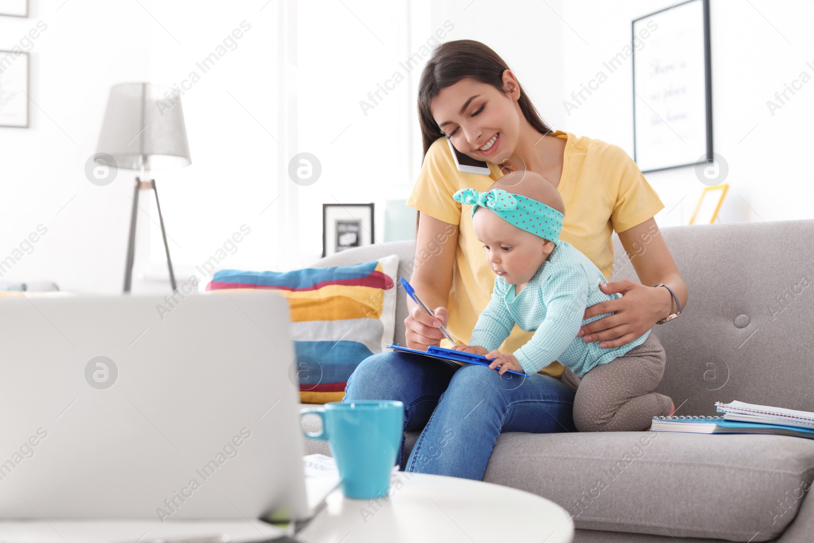 Photo of Young mother with her cute baby girl working at home