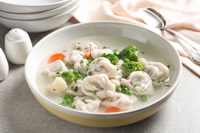 Bowl of tasty dumplings in broth on table