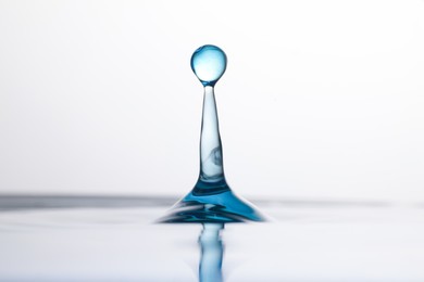 Photo of Splash of clear water with drop on light background, closeup