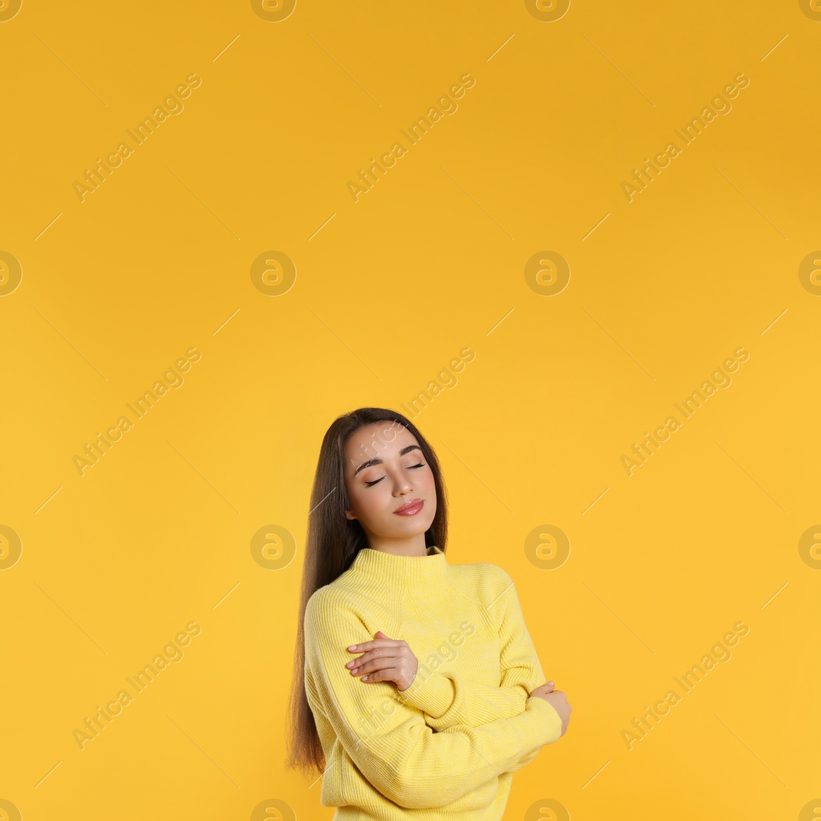 Photo of Beautiful young woman wearing warm sweater on yellow background. Space for text