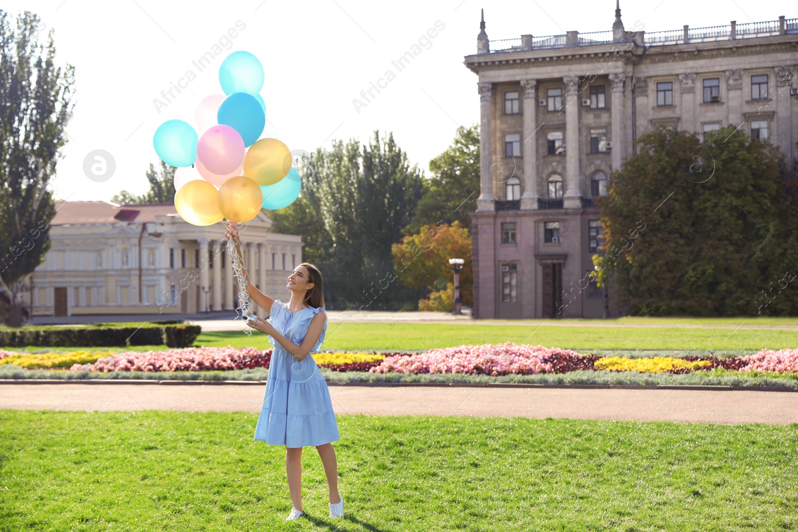 Photo of Beautiful teenage girl holding colorful balloons on street