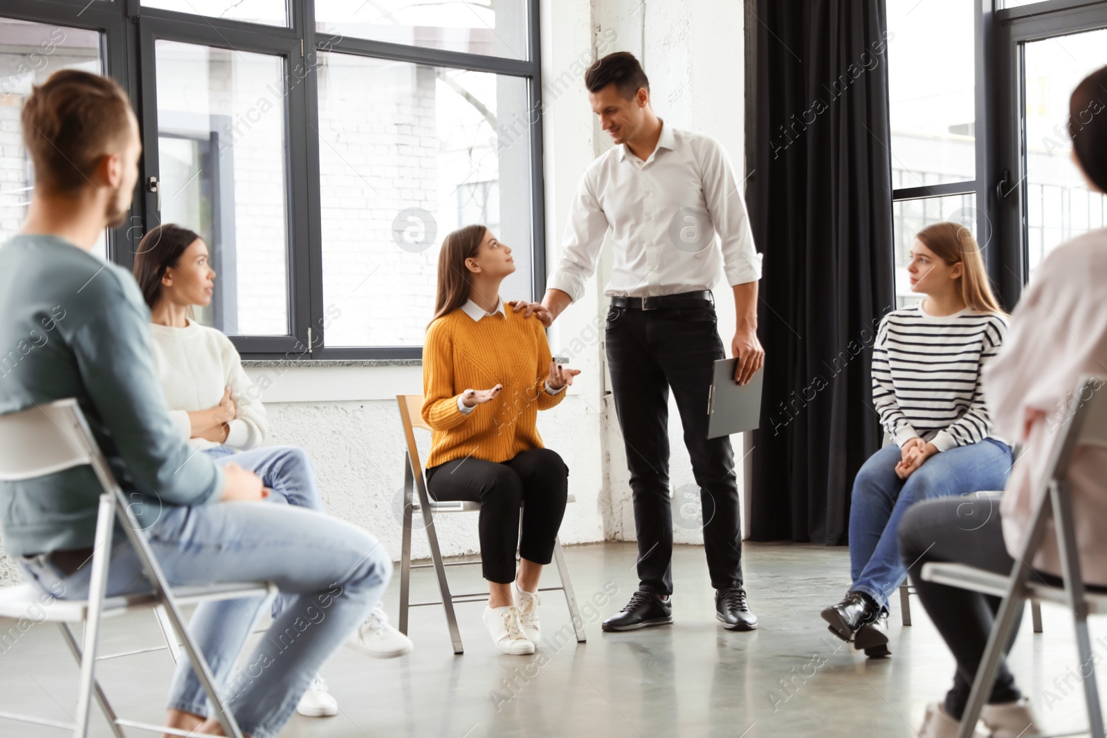 Photo of Psychotherapist working with patients in group therapy session indoors