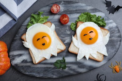 Halloween themed breakfast served on black table, flat lay. Tasty toasts with fried eggs in shape of ghost
