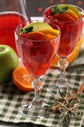 Photo of Christmas Sangria cocktail in glasses and ingredients on table