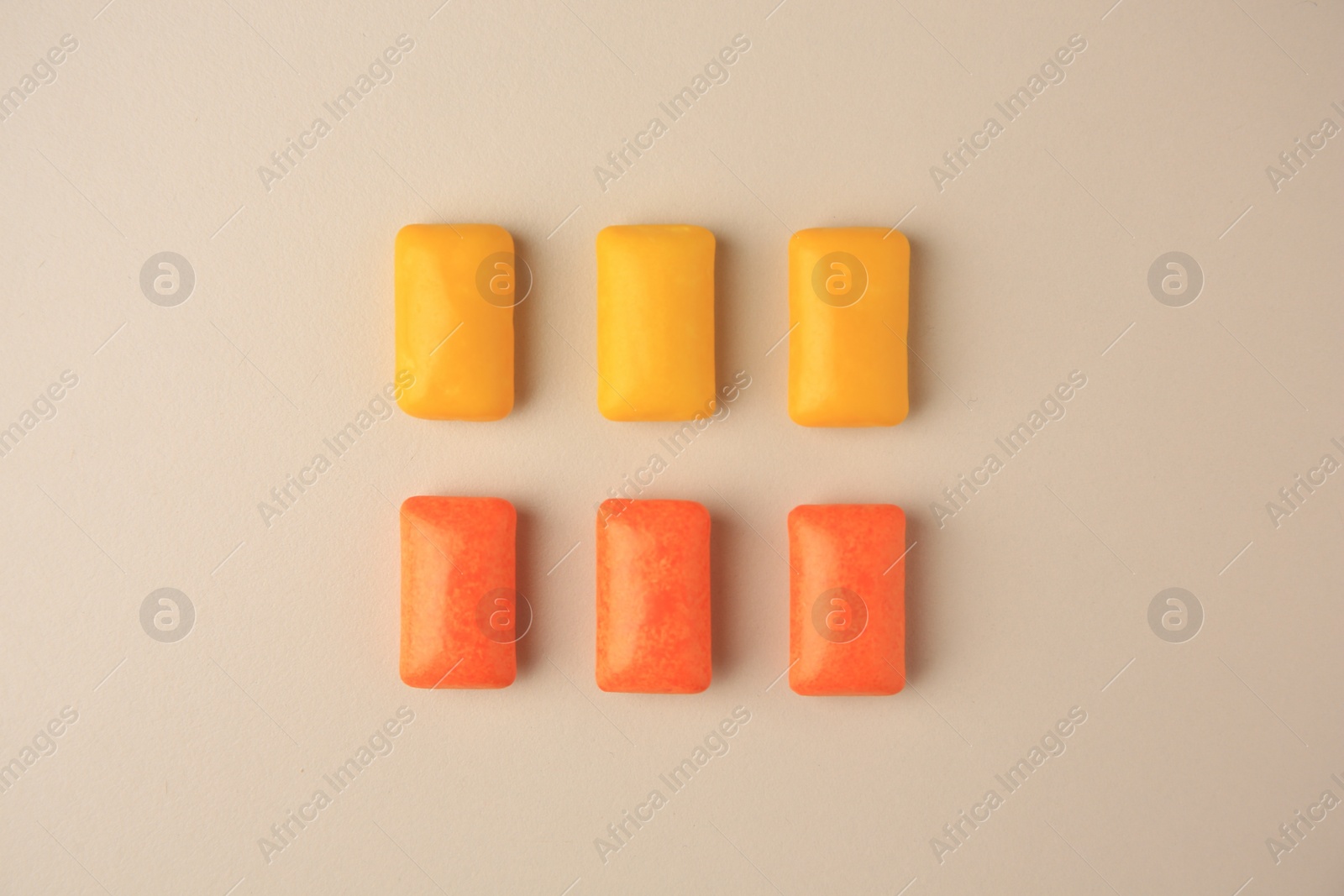 Photo of Tasty chewing gums on beige background, flat lay