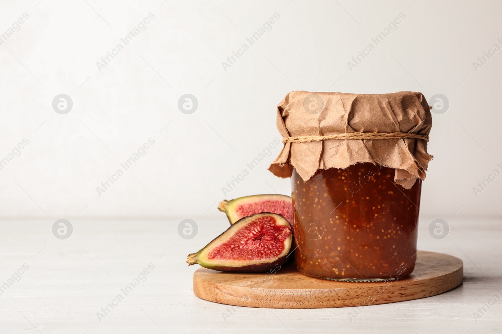 Photo of Fig jam on white wooden table. Space for text
