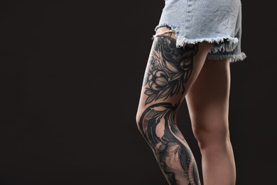 Photo of Woman with cool tattoos on black background, closeup. Space for text