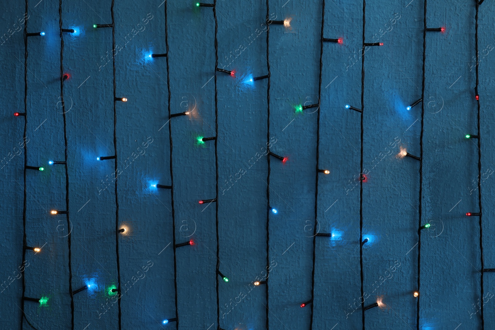 Photo of Beautiful bright Christmas lights on color background