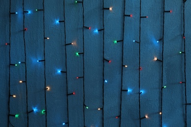 Photo of Beautiful bright Christmas lights on color background