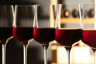 Photo of Glasses of red wine in cellar, closeup. Expensive drink