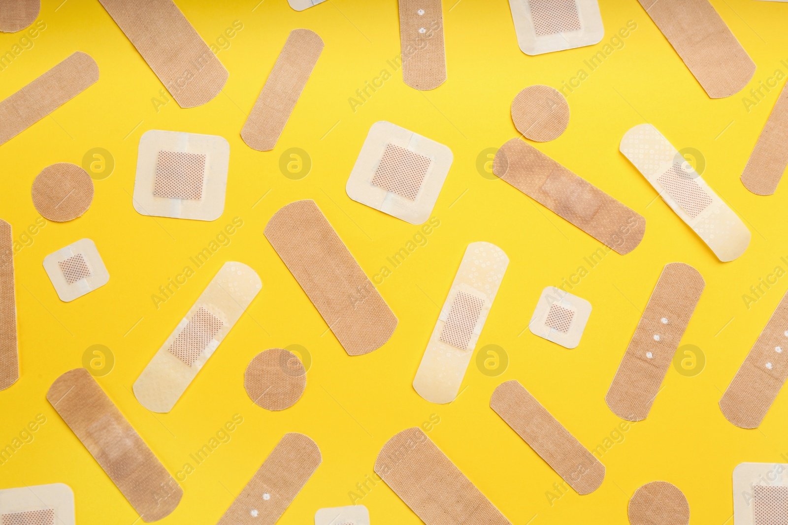Photo of Different types of sticking plasters on yellow background, flat lay