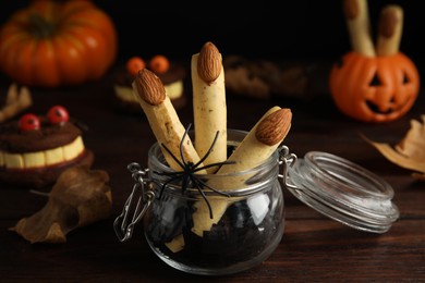Photo of Delicious desserts decorated as monster fingers on wooden table. Halloween treat