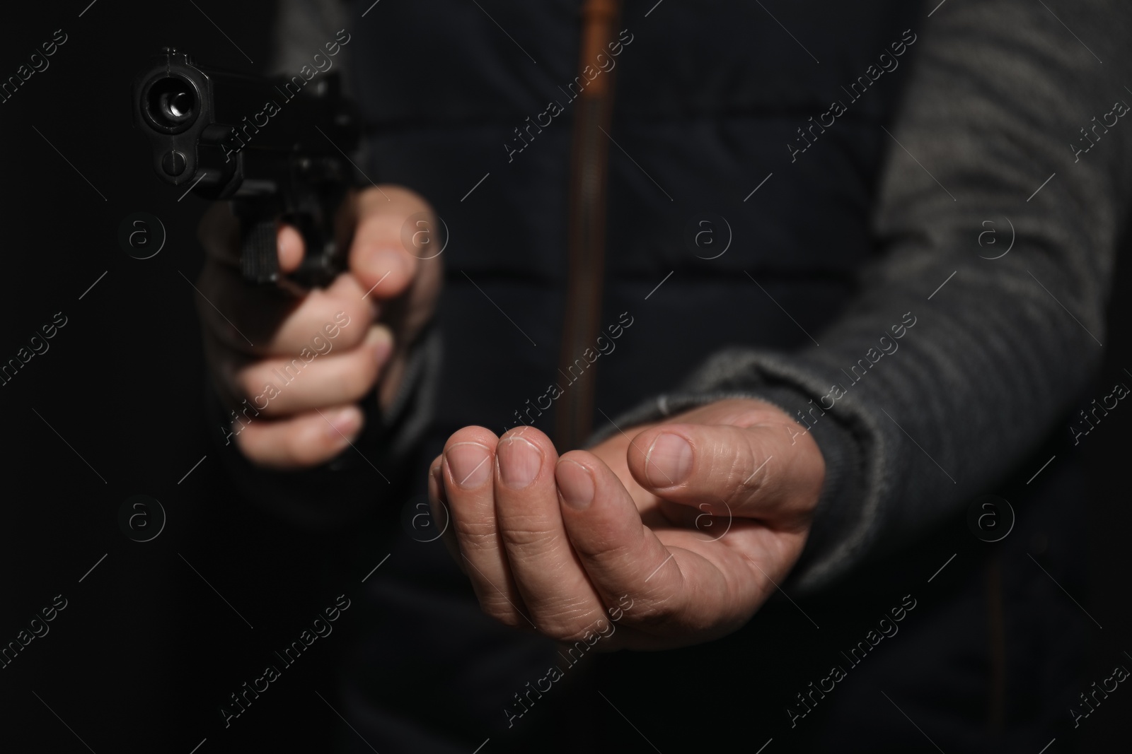 Photo of Dangerous criminal with gun on black background, closeup. Armed robbery