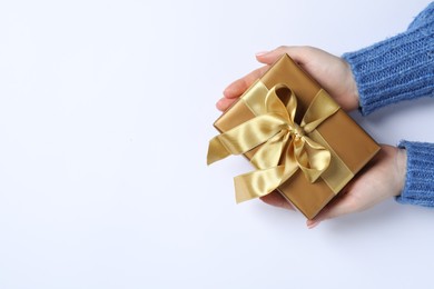 Christmas present. Woman holding gift box on white background, top view. Space for text