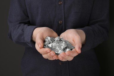 Photo of Woman with silver nuggets on black background, closeup