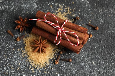 Photo of Different aromatic spices on grey textured table, closeup