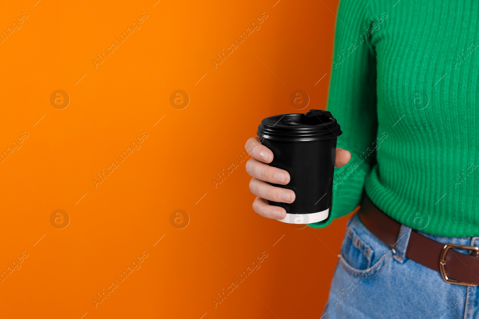 Photo of Woman holding takeaway cup with drink on orange background, closeup view and space for text. Coffee to go