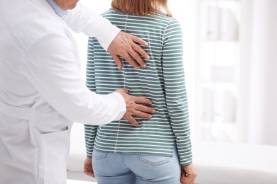 Photo of Chiropractor examining patient with back pain in clinic, closeup