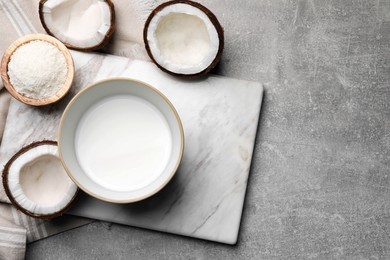 Photo of Bowl of delicious coconut milk, flakes and coconuts on light grey table, flat lay. Space for text