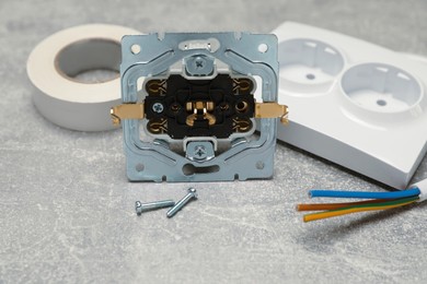 Photo of Disassembled power socket, cable and insulating tape on grey table