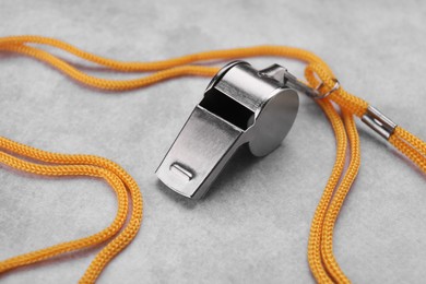 One metal whistle with cord on light grey table, closeup
