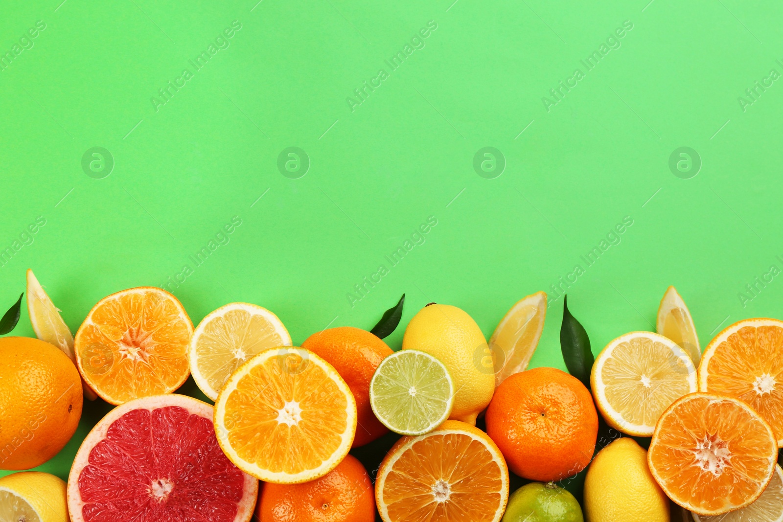 Photo of Flat lay composition with tangerines and different citrus fruits on green background. Space for text