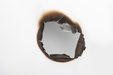 Burnt hole in paper on white background