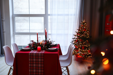 Stylish kitchen interior with festive table and decorated Christmas tree