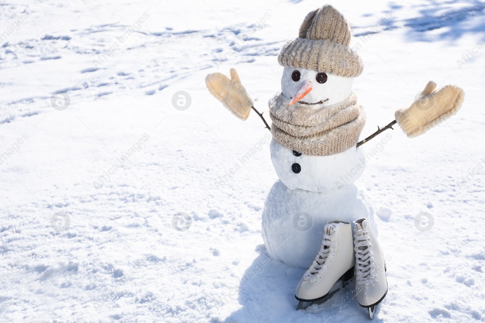 Photo of Funny snowman with hat, mittens and scarf outdoors on sunny day. Space for text