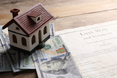 Last Will and Testament, house model and dollar bills on wooden table, closeup