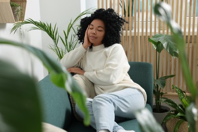 Woman relaxing on sofa near beautiful houseplants at home