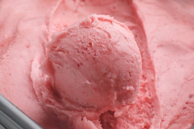 Photo of Scoop of delicious strawberry ice cream in container, closeup