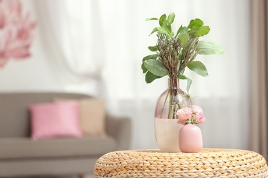 Vases with beautiful bouquets on table in room interior. Space for text
