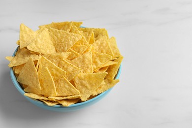 Tortilla chips (nachos) in bowl on white table. Space for text